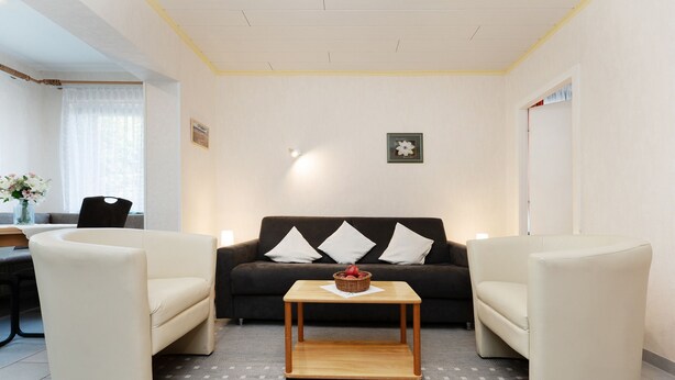En stue med sofa, to lænestole, sofabord og et spiseområde med bord og stole.