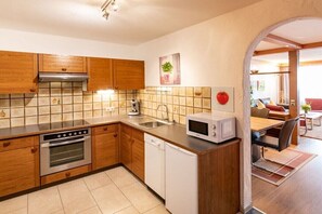 A modern kitchen with wooden cabinets, a stainless steel oven, a dishwasher, and a microwave. - Top 17 for 2-4 people / 2nd floor (Schröcken)