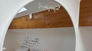 A circular window revealing a bed with a wooden headboard, a bedside table, and a wall with a motivational quote. - Vacation Rental/Apartment for 6 Guests, 62 m², in Freistadt (317570) (Freistadt)