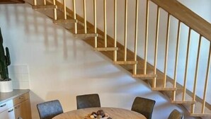 A dining area with a round table and six chairs, a staircase in the background, and a wooden floor. - Vacation Rental/Apartment for 6 Guests, 62 m², in Freistadt (317570) (Freistadt)