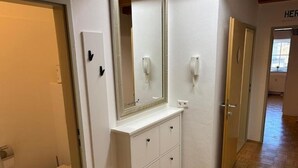 A bathroom with a toilet, a vanity with drawers, a mirror, and a wall-mounted phone. - Vacation Rental/Apartment for 6 Guests, 62 m², in Freistadt (317570) (Freistadt)