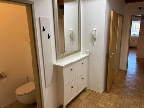A bathroom with a toilet, a vanity with drawers, a mirror, and a wall-mounted phone. - Vacation Rental/Apartment for 6 Guests, 62 m², in Freistadt (317570) (Freistadt)