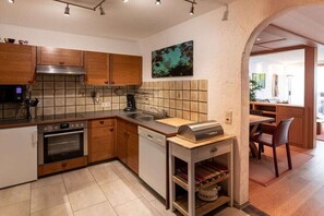 Eine moderne Küche mit Holzschränken, einem Backofen, einem Geschirrspüler und einer Grillstation.
