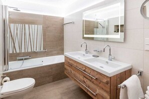 Ein modernes Badezimmer mit einem Doppelwaschbecken, einer Badewanne und einer Toilette.