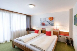 Ein Doppelbett mit zwei Kissen, ein Nachttisch mit einer Lampe und ein an der Wand hängendes Kunstwerk.