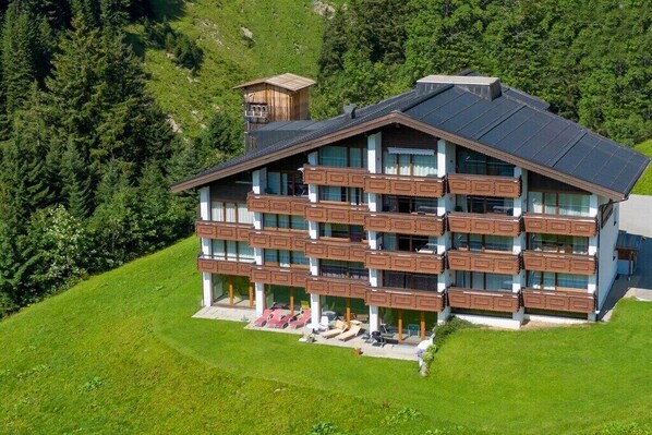 Ein mehrstöckiges Hotel mit Balkonen, einer Seilbahn und einer Bergkulisse.