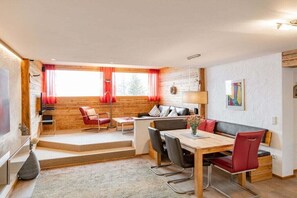 A modern interior with a wooden wall, a dining area with a table and chairs, a sofa, and a TV. - Top 20 for 4-6 people / 2nd floor (Schröcken)