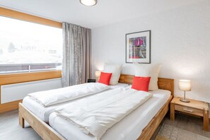 Une chambre d’hôtel avec un lit, deux tables de chevet, une fenêtre avec des rideaux et un tableau encadré au mur.