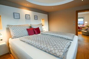 A modern bedroom with a double bed, two bedside tables, and a nightstand. - Holiday home in Rauris with swimming pool (Rauris)