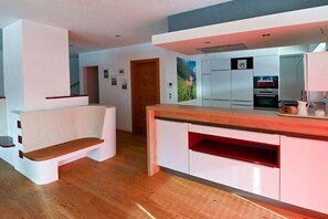 A modern kitchen with white cabinetry, a wooden countertop, and a built-in oven. - Holiday home in Rauris with swimming pool (Rauris)