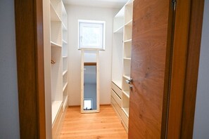 A narrow hallway with wooden flooring leading to a closet with open shelves and a mirror. - Holiday home in Rauris with swimming pool (Rauris)