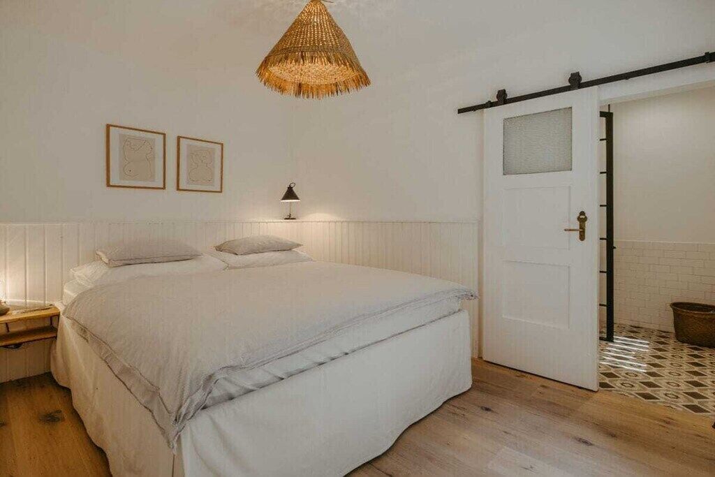 Une chambre à coucher avec un lit, une table de chevet, une lampe et une porte.