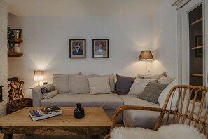 Un saló acollidor amb un sofà, una taula de centre i una làmpada. Hi ha imatges emmarcades a la paret i un cist de llenya.