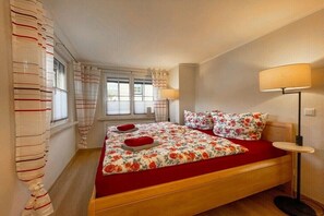 A bedroom with a bed, curtains, a bedside lamp, and a window. - Holiday home with 1 bedroom (Rudolstadt \/ OT Eichfeld)