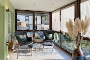 Ein Balkon mit zwei Stühlen, einem kleinen Tisch und einer Vase mit Pampasgras.