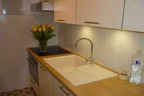 Eine Küche mit einem Spülbecken, einer Vase voller gelber Tulpen und einer Wasserflasche.