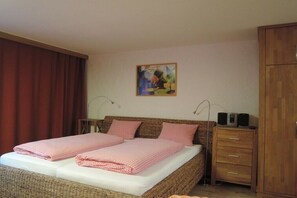 Ein Doppelbett mit karierter Bettwäsche, ein Nachttisch mit Lautsprechern und ein Holzschrank.