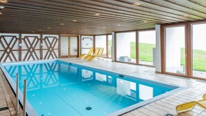 En swimmingpool med træloft og store vinduer.