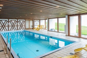 Una piscina con tetto in legno e ampie finestre.