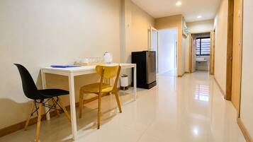 A clean, modern kitchen with a white countertop, a black refrigerator, and a wooden chair.