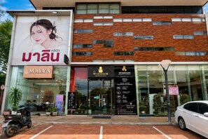 A modern building with a clinic, hostel, and a large advertisement. - Wisdom Muangthong Hostel (Pak Kret)