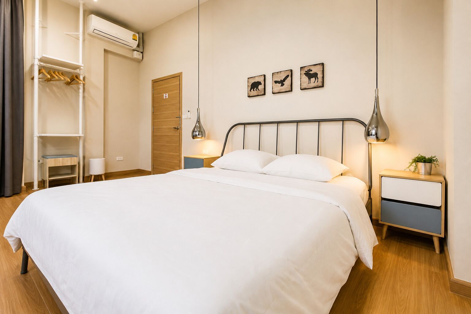 Una cama bien tendida con ropa blanca, una mesita de noche con lámpara y un estante en la pared con un espejo.