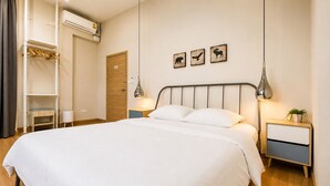 A neatly made bed with white linens, a bedside table with a lamp, and a wall-mounted shelf with a mirror. - Wisdom Muangthong Hostel (Pak Kret)