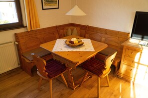 A wooden dining table with a fruit bowl centerpiece, surrounded by cushioned chairs. - Vrbo Property (Ehrwald)