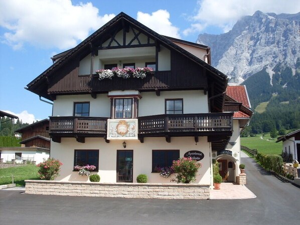 A two-story building with balconies, a sign indicating it's an apartment, and a mountain backdrop. - Vrbo Property (Ehrwald)