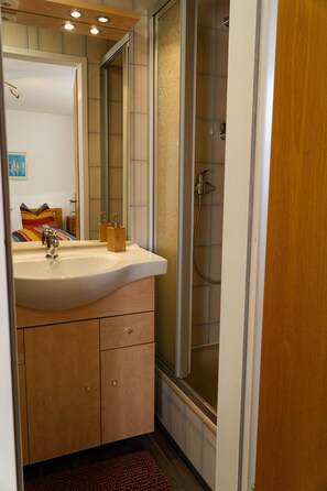 A bathroom with a sink, mirror, and shower. - Vrbo Property (Ehrwald)