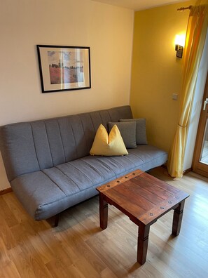 A living room with a grey sofa, a wooden coffee table, and a framed picture on the wall. - Vrbo Property (Ehrwald)