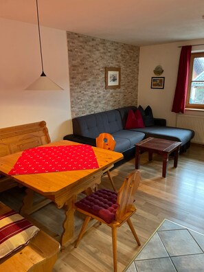 A cozy living room with a wooden dining table, a sofa, and a red and white patterned table runner. - Vrbo Property (Ehrwald)