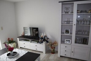 A modern living room with a flat-screen TV, white cabinetry, and decorative items. - Holiday home with 2 bedrooms (Burg (Spreewald))