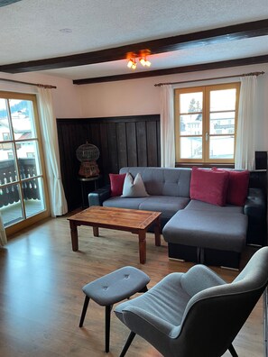A living room with a wooden coffee table, grey sofa, and a grey armchair. - Vrbo Property (Ehrwald)