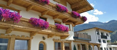 A hotel with a sign reading 'HAUS Gatterland,' balconies with flower boxes, and a mountainous backdrop.