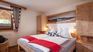 A bedroom with a bed, wooden headboard, a window with curtains, a wall-mounted picture, and a nightstand with a lamp. - Holiday apartment with 3 bedrooms (Zell am Ziller)
