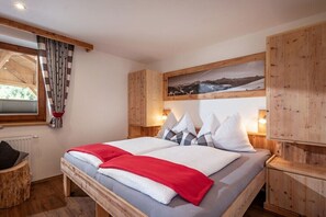 A bedroom with a bed, wooden headboard, a window with curtains, a wall-mounted picture, and a nightstand with a lamp. - Holiday apartment with 3 bedrooms (Zell am Ziller)