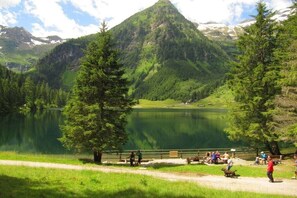 A lake surrounded by mountains with a path and people around. - Self-catering hut Potzalm (Kleinsölk)