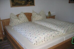 A double bed with floral bedding, a wooden headboard, and a nightstand with a lamp. - Self-catering hut Potzalm (Kleinsölk)