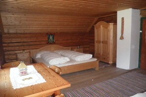 A wooden cabin bedroom with a bed, a nightstand, a wooden wardrobe, and a small table with a doily. - Self-catering hut Potzalm (Kleinsölk)