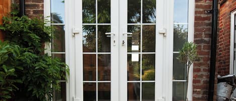 A brick building with a wooden deck leading to a set of white double doors.