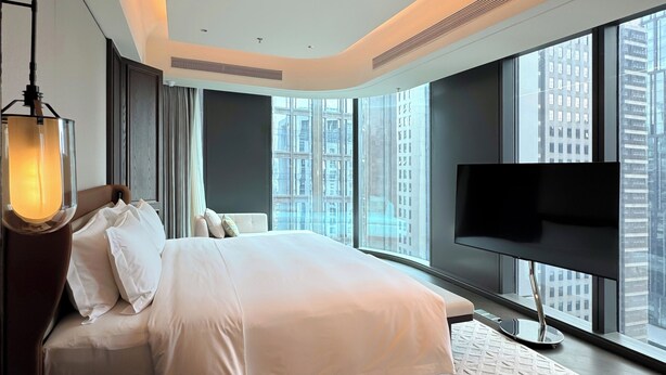 Ein modernes Hotelzimmer mit einem großen Bett, einem Flachbildfernseher und Blick auf die Stadt.