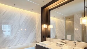 Ein modernes Badezimmer mit einem großen Spiegel, einer Badewanne und einem Waschtisch.