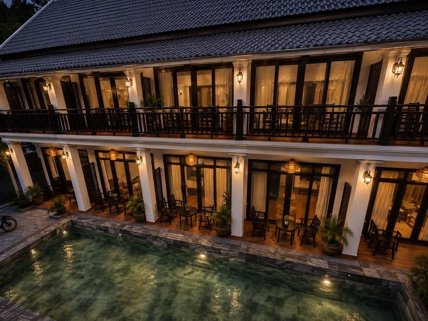 A two-story building with a swimming pool, outdoor seating, and a balcony.