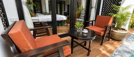 Un área de estar moderna al aire libre con vista a la piscina, con una mesa, una planta, una taza y dos sillones con cojines.