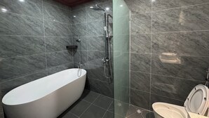 Et moderne badeværelse med et fristående badekar, bruser og toilet.