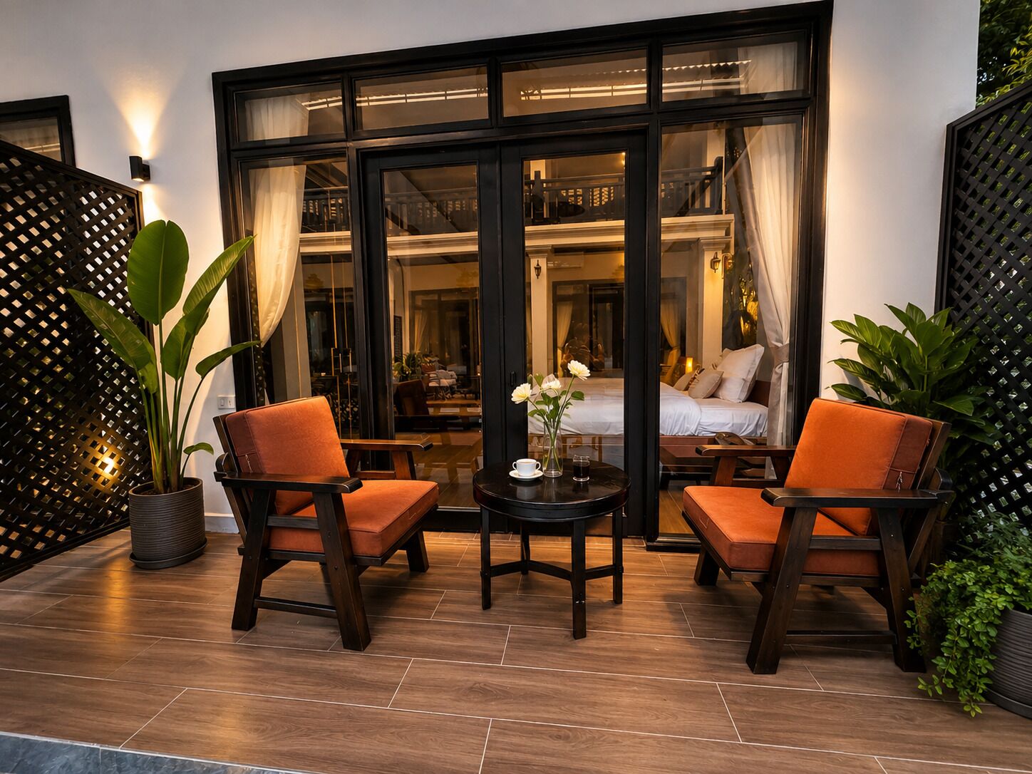 A hotel room with a large window, a sofa, a small table with a vase, and a potted plant.