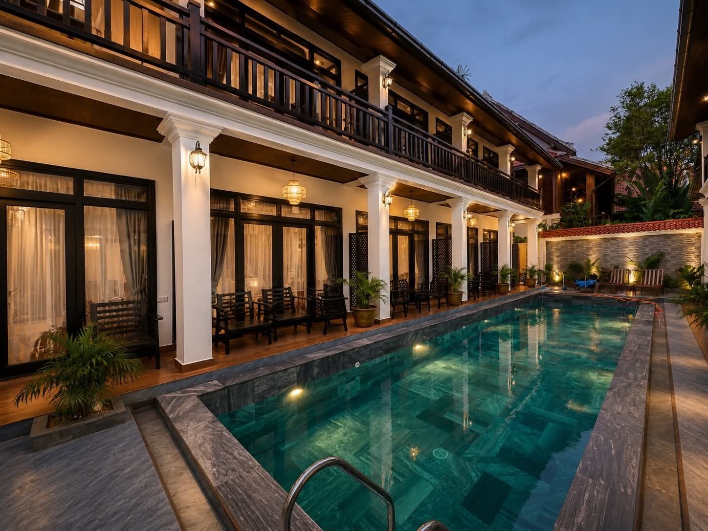 A hotel with a swimming pool, outdoor seating, and a covered patio area.
