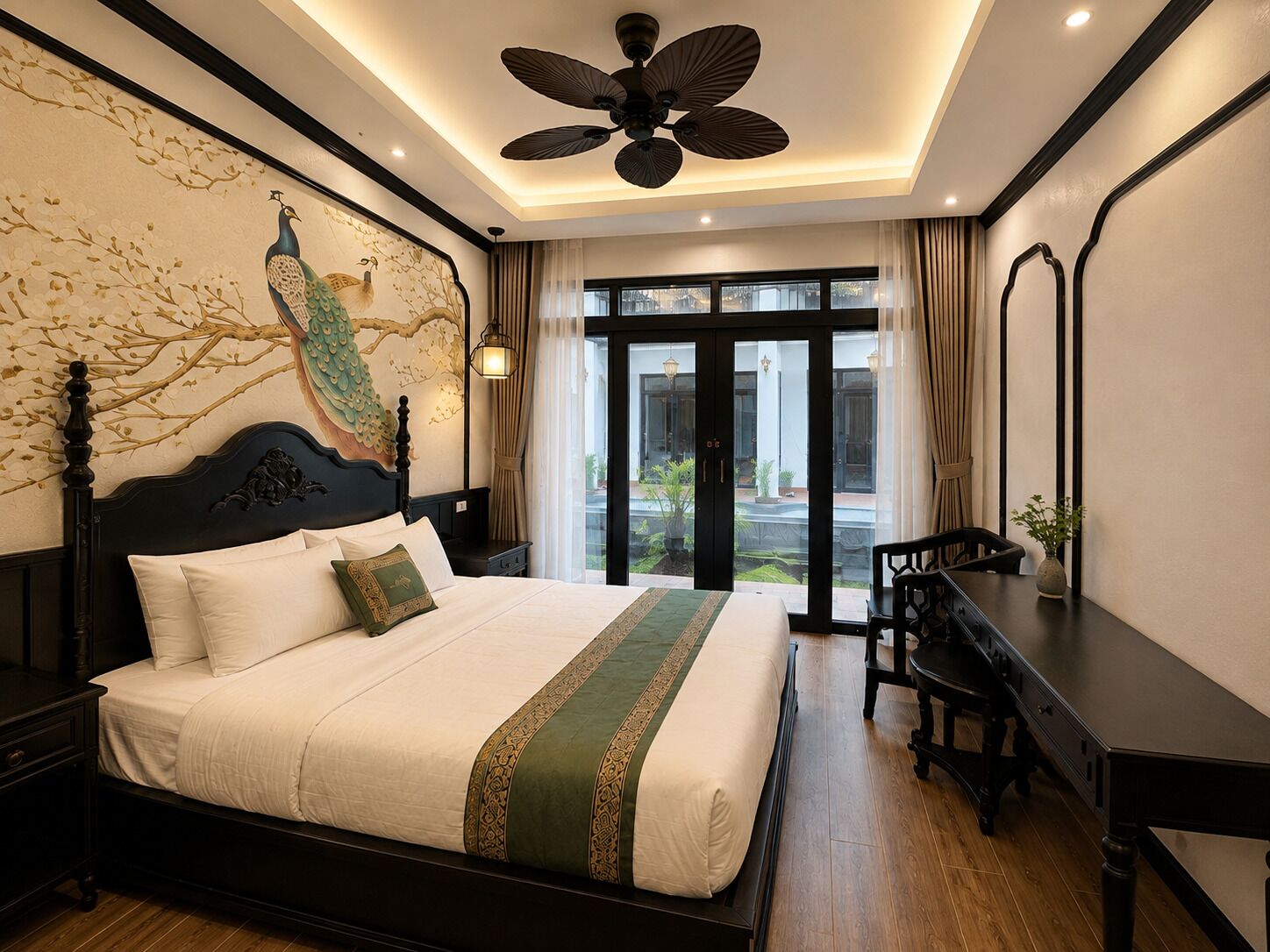A hotel room with a large bed, a desk, a chair, a ceiling fan, and a view of the outdoors.