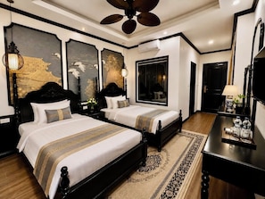 A hotel room with two beds, a large mirror, a ceiling fan, and artwork on the walls. - Luang Prabang Indochine Heritage Hotel (Luang Prabang)